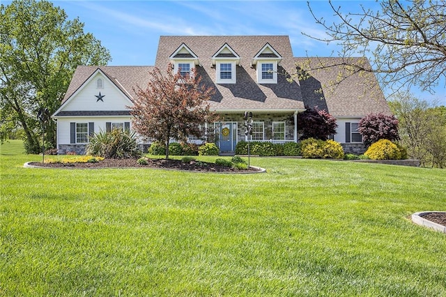 cape cod-style house featuring roof with shingles, a front yard, and stone siding