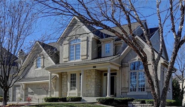 traditional-style home with a porch, a shingled roof, and stone siding