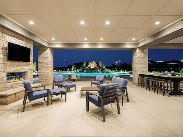 patio at twilight with an outdoor stone fireplace and outdoor dry bar