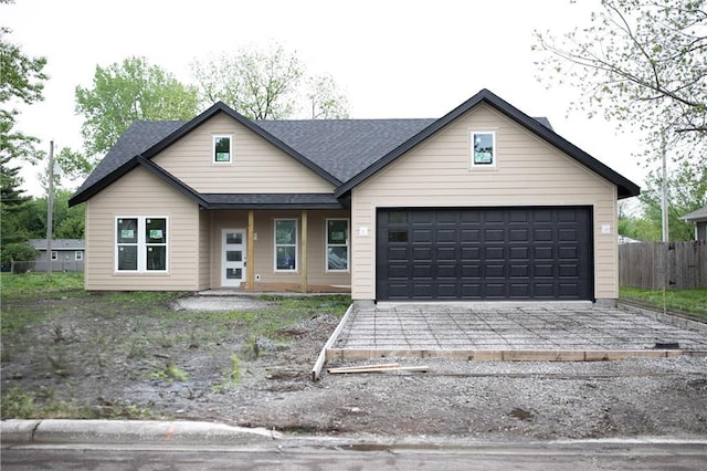 view of front facade featuring fence, driveway, a shingled roof, and a garage