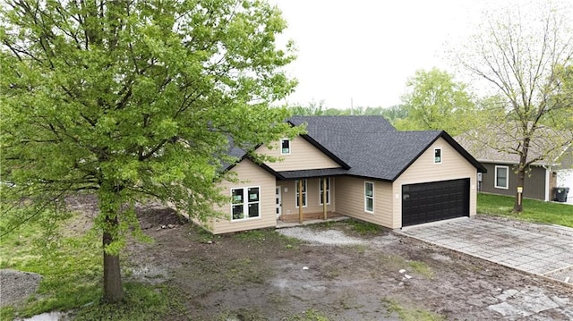 view of front of house featuring an attached garage, driveway, and a shingled roof