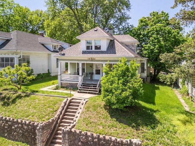 view of front of home featuring stairway, a porch, a front lawn, a shingled roof, and a chimney