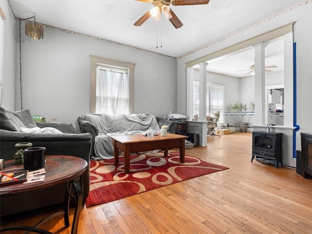living area with a ceiling fan, wood-type flooring, and decorative columns