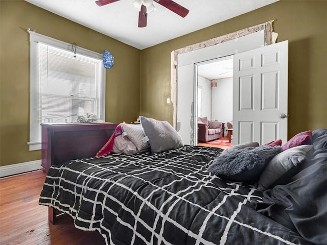 bedroom featuring wood finished floors, baseboards, and a ceiling fan