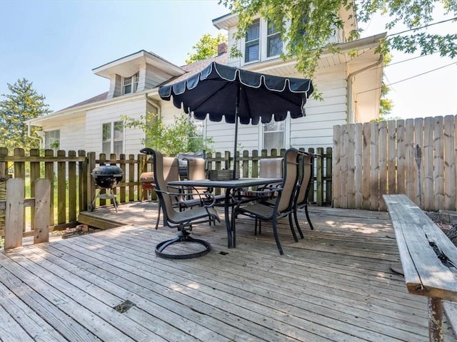 wooden terrace featuring outdoor dining space, area for grilling, and fence