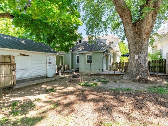 rear view of house with fence, a fire pit, and a wooden deck