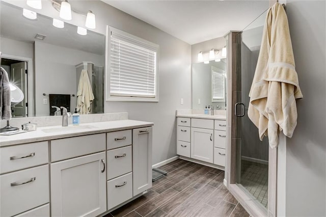 925 SW Ovation Dr, Lees Summit, MO 64081 - bathroom with wood tiled floor, a shower stall, two vanities, a sink, and baseboards