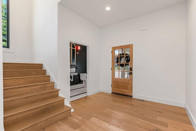 foyer entrance with baseboards, recessed lighting, light wood-style flooring, and stairway