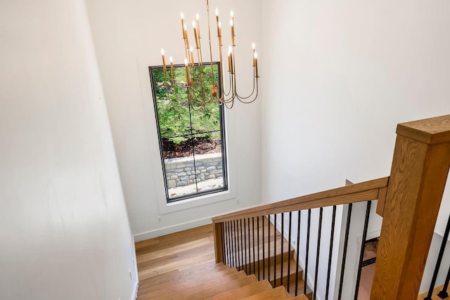staircase with baseboards, a chandelier, and wood finished floors
