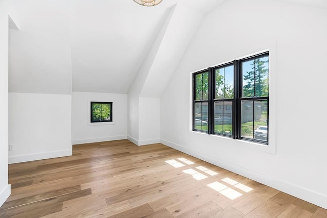 additional living space featuring baseboards, vaulted ceiling, and light wood finished floors