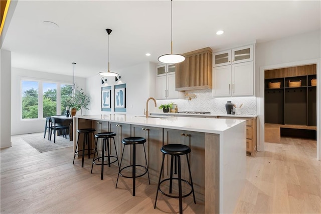 10675 W 142nd Ter, Overland Park, KS 66221 - kitchen with decorative backsplash, light wood finished floors, a spacious island, light countertops, and a breakfast bar area