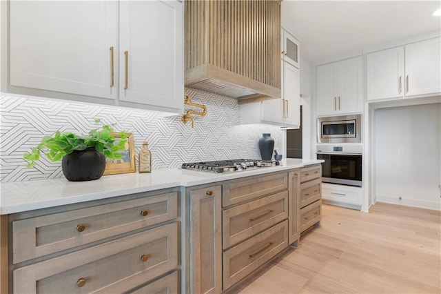 10675 W 142nd Ter, Overland Park, KS 66221 - kitchen featuring appliances with stainless steel finishes, decorative backsplash, light countertops, light wood-type flooring, and white cabinetry