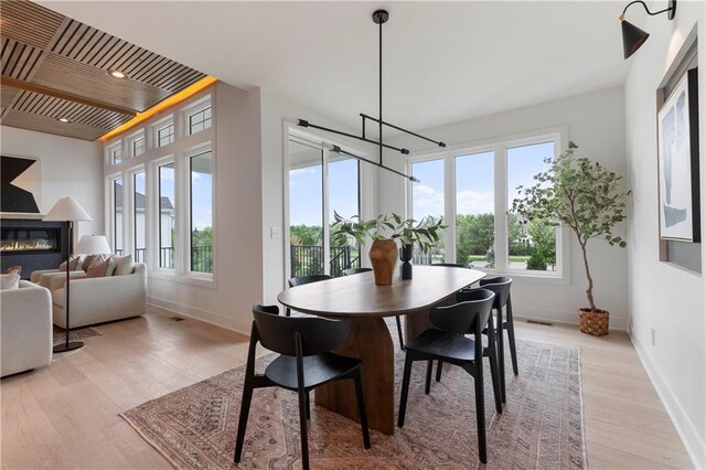 10675 W 142nd Ter, Overland Park, KS 66221 - dining room with healthy amount of natural light, light wood-style flooring, a glass covered fireplace, and a chandelier
