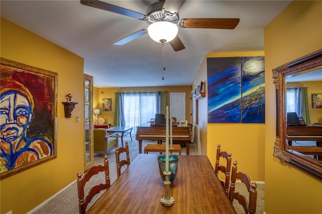 dining space with ceiling fan, baseboards, and carpet