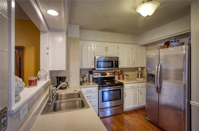 kitchen featuring white cabinets, stainless steel appliances, a sink, and light countertops