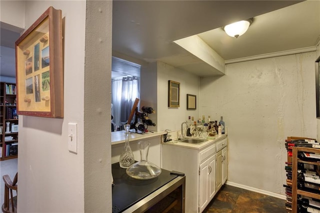 bar with stone finish floor, wet bar, a sink, baseboards, and wine cooler