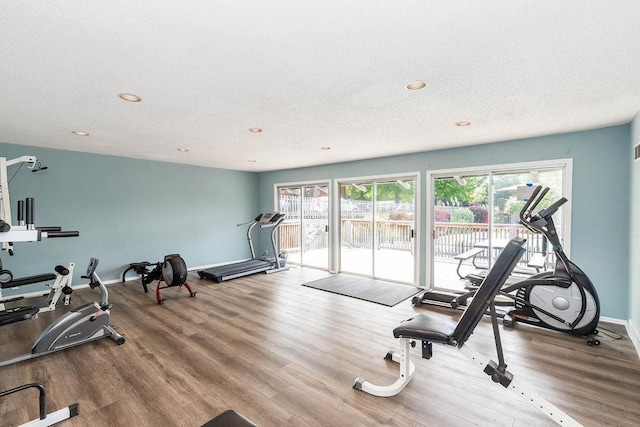 exercise area featuring recessed lighting, baseboards, a textured ceiling, and wood finished floors
