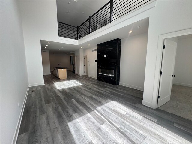 22150 W 116th Ter, Olathe, KS 66061 - unfurnished living room featuring baseboards, a sink, a towering ceiling, and wood finished floors