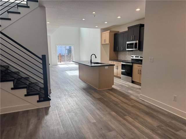 kitchen featuring a sink, wood finished floors, dark countertops, and stainless steel appliances