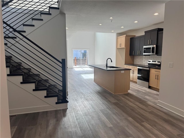kitchen featuring a sink, appliances with stainless steel finishes, wood finished floors, and dark countertops