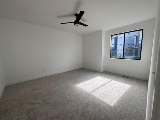 carpeted spare room with baseboards, a ceiling fan, and visible vents