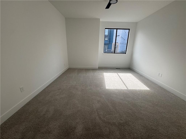 empty room with baseboards, ceiling fan, and light carpet