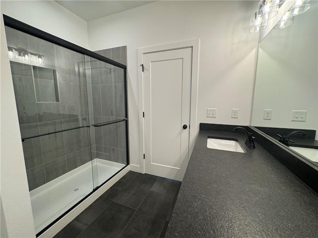 bathroom featuring baseboards, a sink, and a shower stall