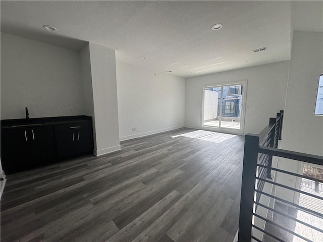 unfurnished living room with visible vents, baseboards, recessed lighting, a sink, and dark wood finished floors