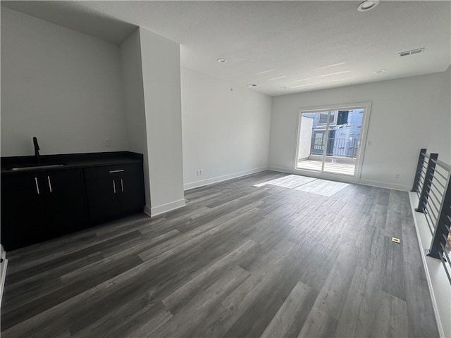 unfurnished living room with visible vents, wood finished floors, baseboards, recessed lighting, and a sink