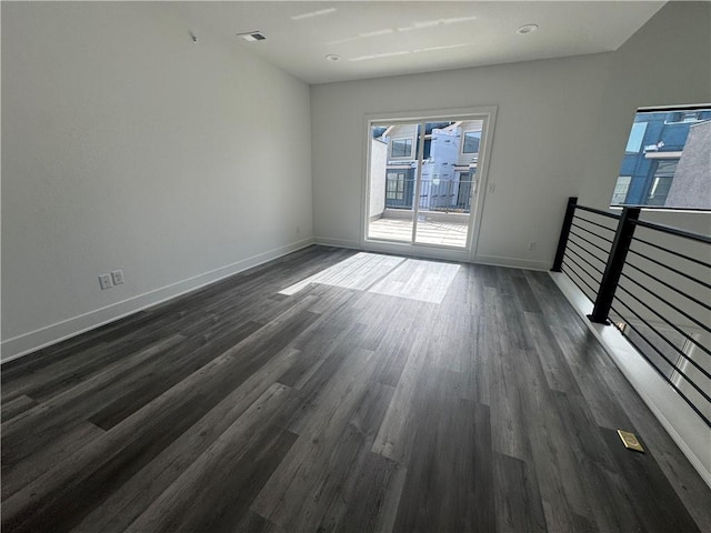 empty room with dark wood-style flooring, baseboards, and visible vents