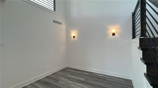 interior space with baseboards, a high ceiling, wood finished floors, and visible vents