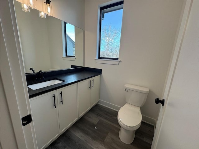 bathroom with baseboards, vanity, toilet, and wood finished floors