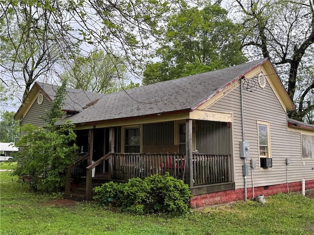 view of front facade with a front lawn, roof with shingles, covered porch, and crawl space