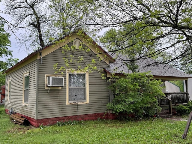 view of side of home with a yard, a deck, and a wall unit AC