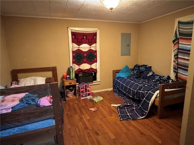 bedroom with baseboards, ornamental molding, wood finished floors, and electric panel
