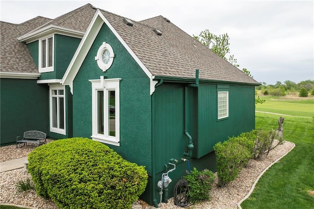 view of side of home with a yard, roof with shingles, and stucco siding