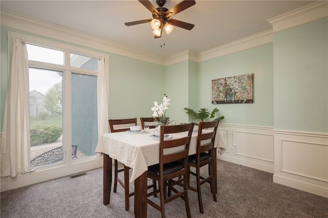 dining room featuring ornamental molding, a ceiling fan, dark carpet, and visible vents