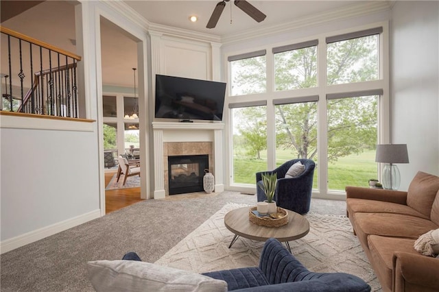 living area with carpet flooring, a ceiling fan, a tiled fireplace, and a wealth of natural light