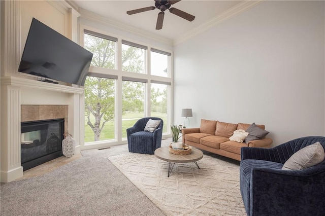 living room with ceiling fan, carpet, a healthy amount of sunlight, a towering ceiling, and ornamental molding