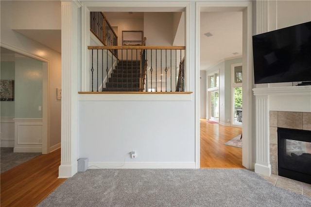 unfurnished living room featuring baseboards, stairs, wood finished floors, and a tile fireplace