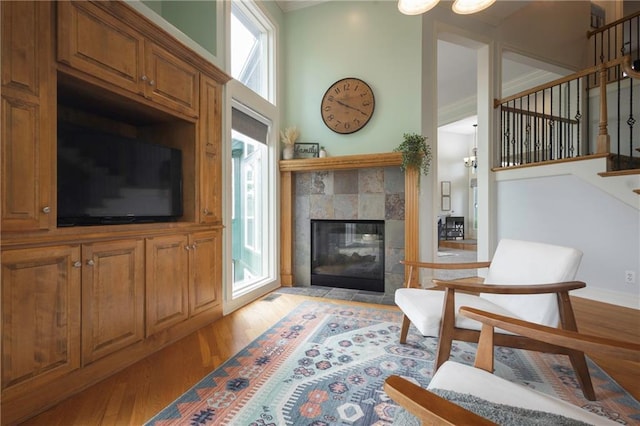 living room featuring stairs, baseboards, a tiled fireplace, and light wood-style floors