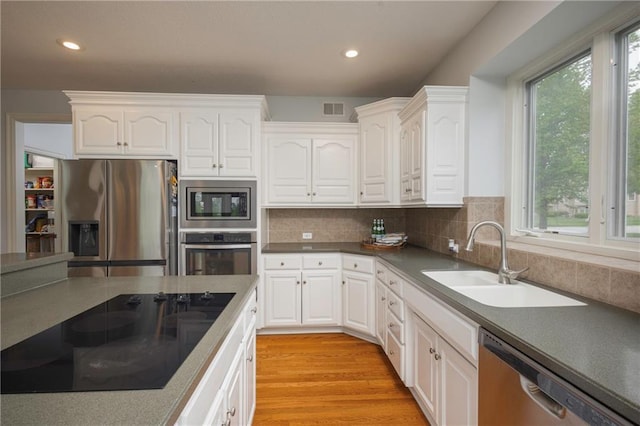 kitchen featuring stainless steel appliances, visible vents, white cabinetry, and a sink