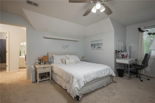 bedroom featuring ceiling fan, visible vents, light colored carpet, lofted ceiling, and ensuite bath