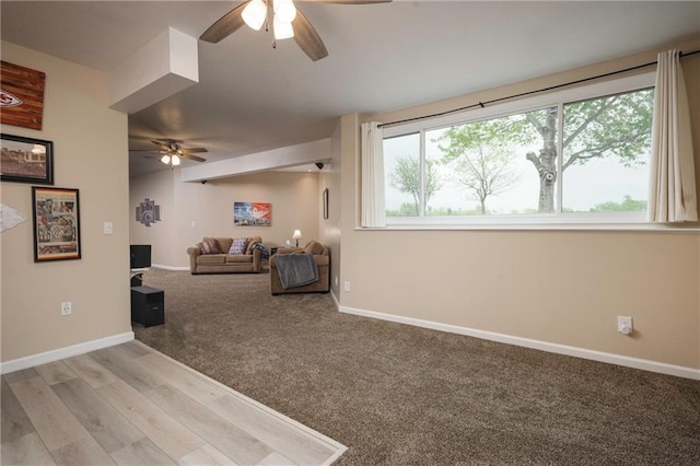 carpeted living area with baseboards and ceiling fan