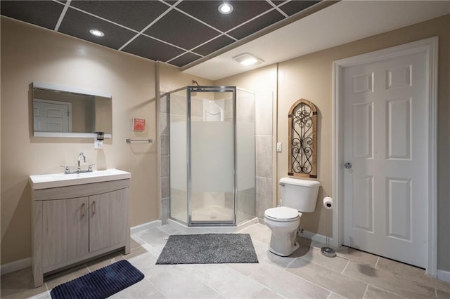 bathroom with tile patterned flooring, vanity, toilet, baseboards, and a shower stall