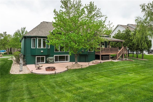 rear view of property with a lawn, a deck, stairway, a patio, and a fire pit