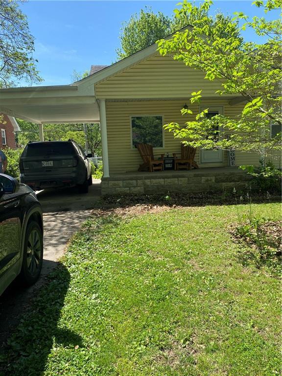 1404 S Barrett Ave, Sedalia, MO 65301 - view of property exterior featuring a lawn, an attached carport, a porch, and driveway