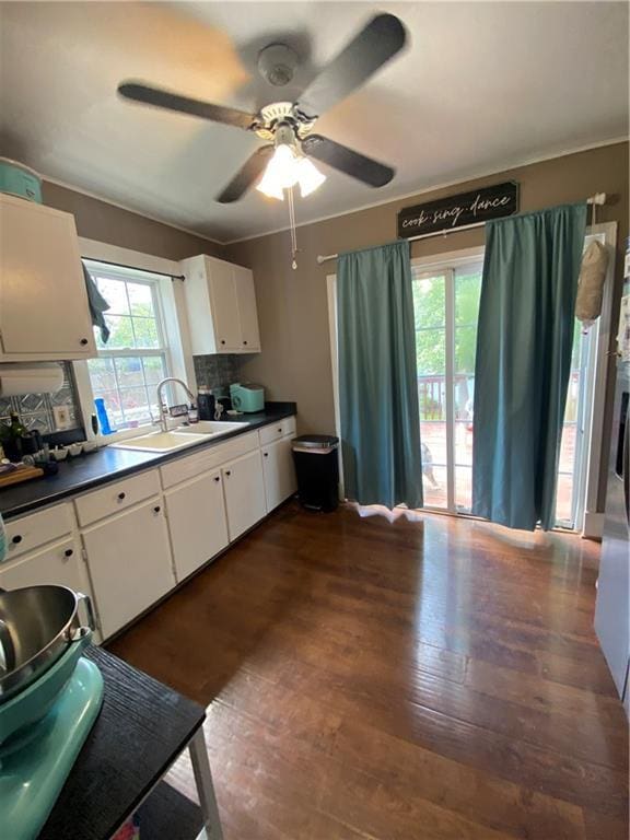 1404 S Barrett Ave, Sedalia, MO 65301 - kitchen with dark countertops, ceiling fan, dark wood-style floors, white cabinets, and a sink