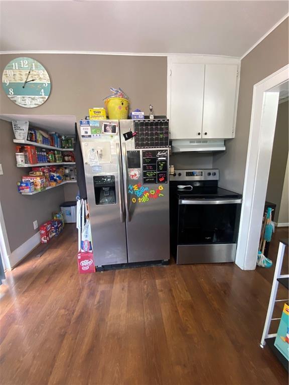 1404 S Barrett Ave, Sedalia, MO 65301 - kitchen with appliances with stainless steel finishes, wood finished floors, white cabinets, ornamental molding, and under cabinet range hood