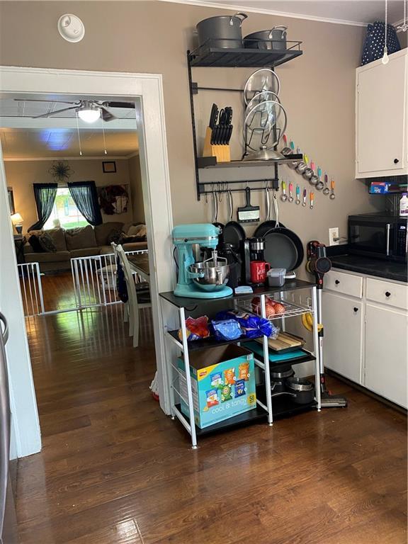 1404 S Barrett Ave, Sedalia, MO 65301 - kitchen with black microwave, white cabinets, and dark wood-style flooring